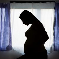 Silhouette of pregnant woman in her bedroom